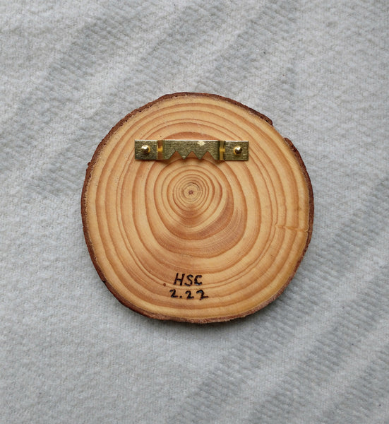 A slice of wood with a hook on the back to demonstrate its possible use as wall decor.