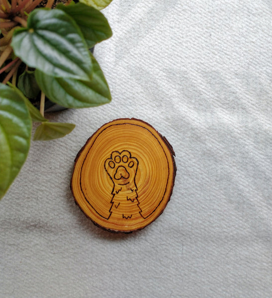 A Cat Paw Wood Slice Coaster with a shaggy cat paw design wood burned into it.