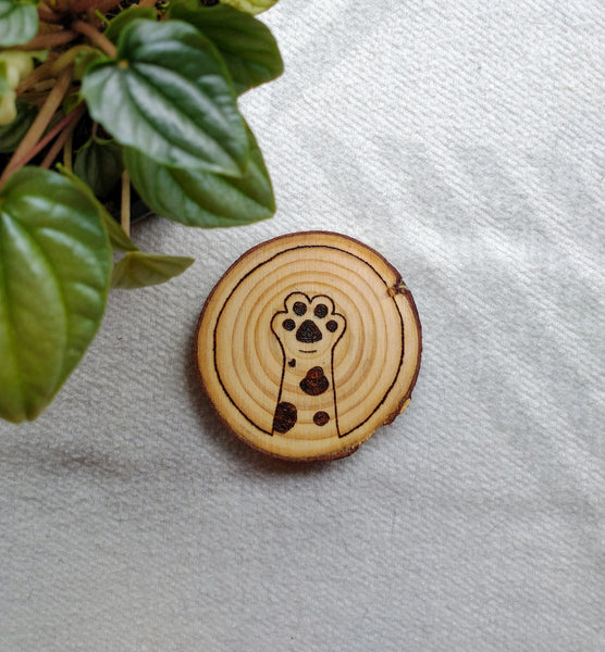 A spotty cat paw design wood burned into a Cat Paw Wood Slice Coaster.