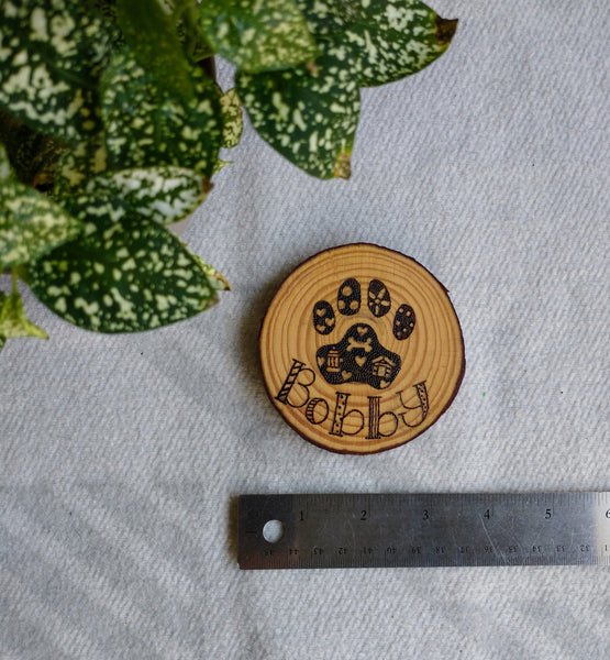 A Custom Dog Paw Print Ornament with a ruler under it to demonstrate its dimensions.